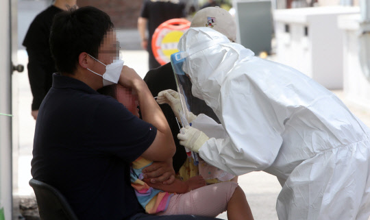 최근 코로나19가 급속도로 확산하면서 어린이집 원생까지 확진 판정을 받은 것과 관련해 20일 강릉시보건소 선별진료소에서 아이가 부모와 함께 검사를 받고 있다. 연합뉴스